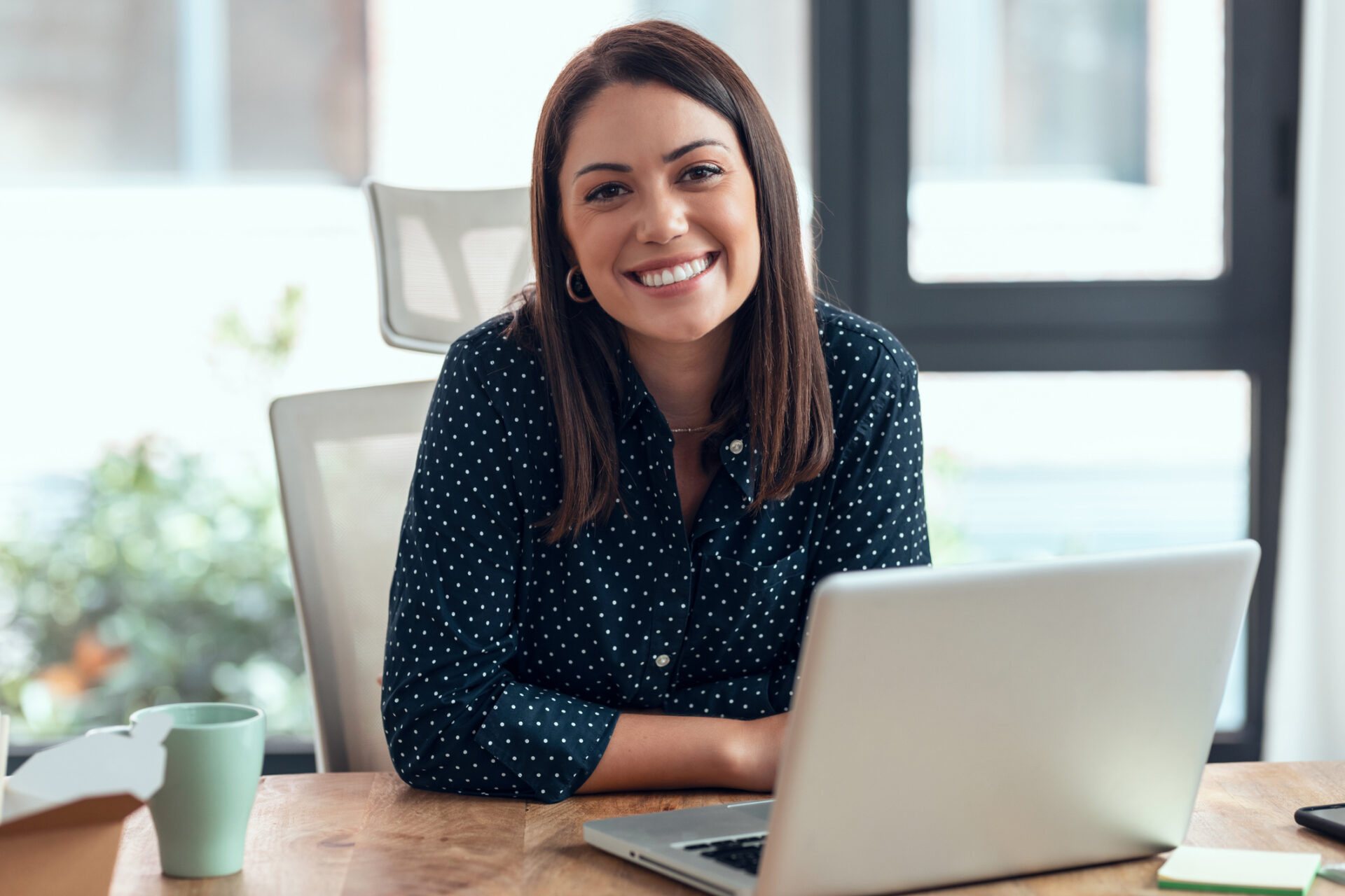 Smiling business woman working with laptop in modern startup office