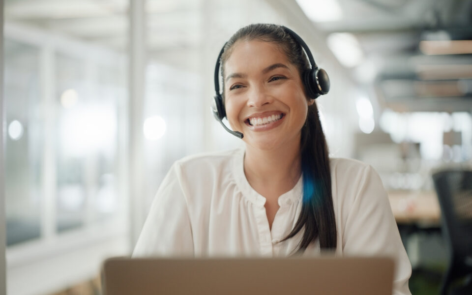 Woman with a headset on working on her computer, happy and relieved that Documo makes faxing easy