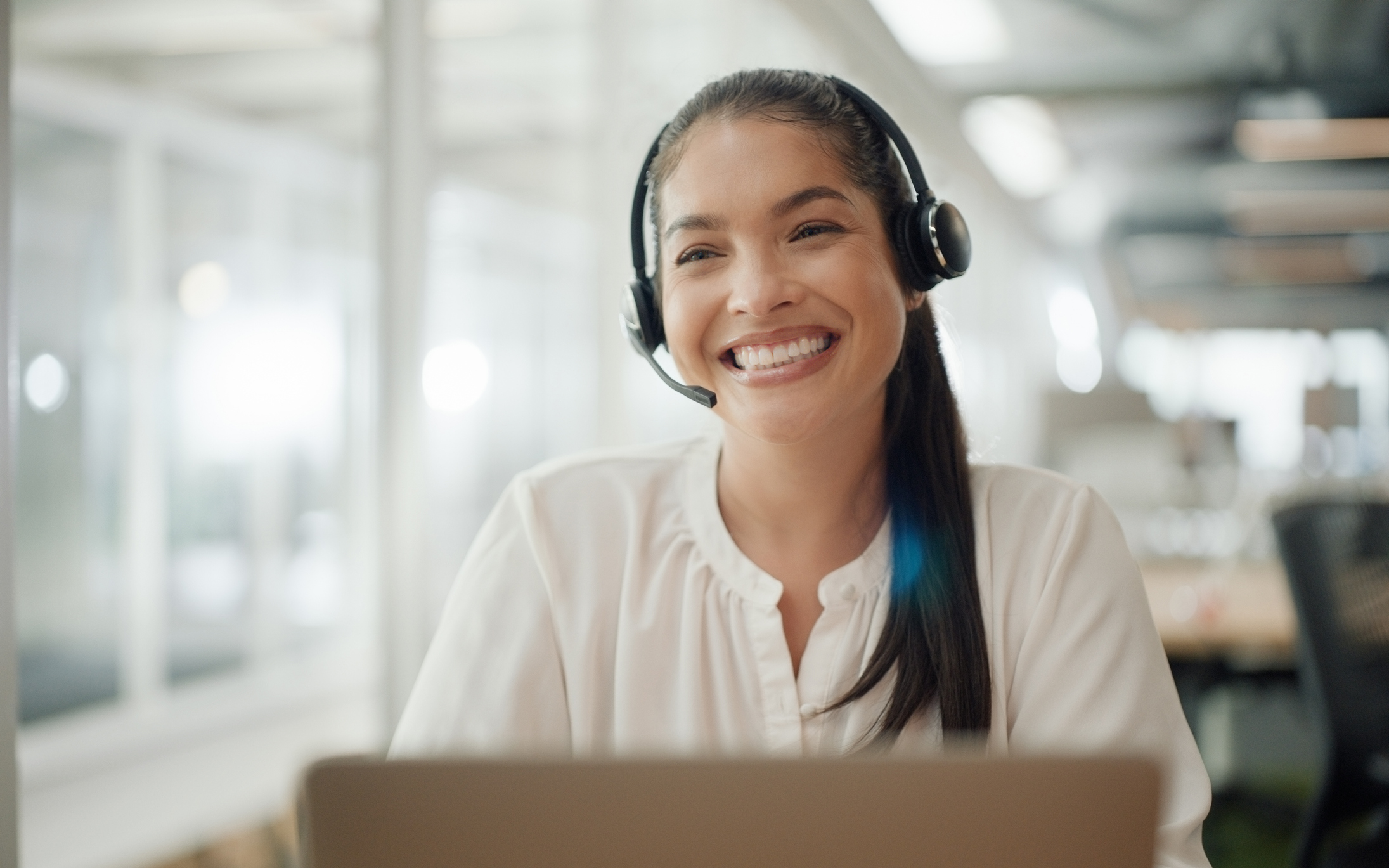 Woman with a headset on working on her computer, happy and relieved that Documo makes faxing easy