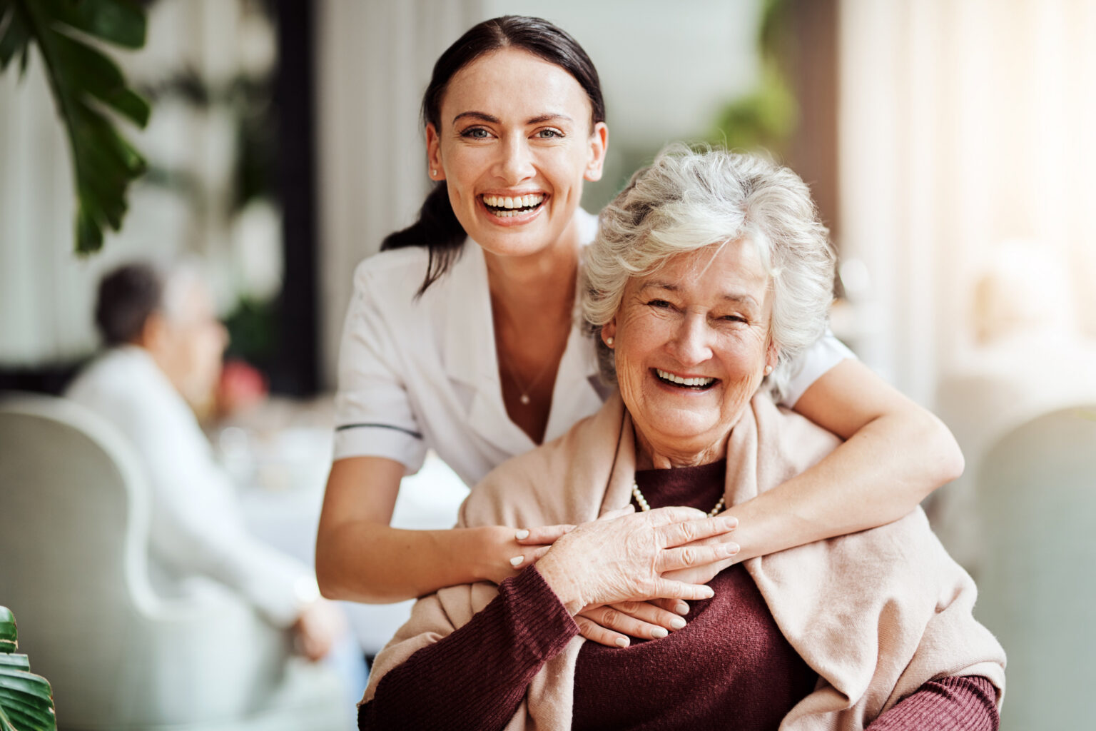 Portrait of a young nurse embracing an elderly woman in a retirement home