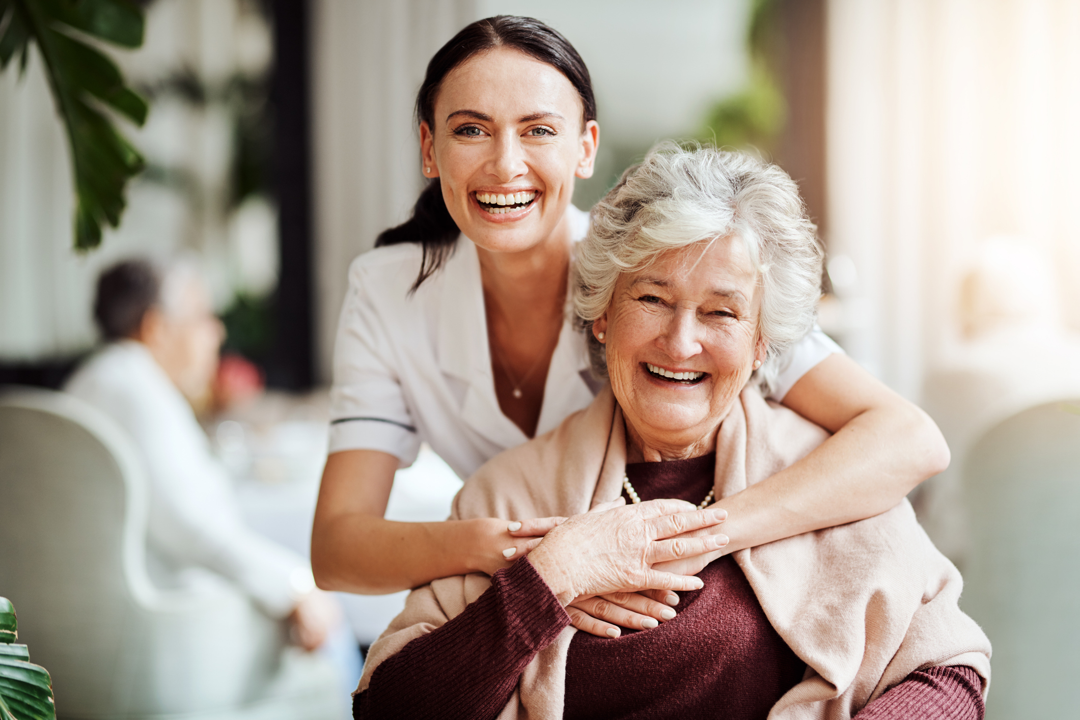 Portrait of a young nurse embracing an elderly woman in a retirement home