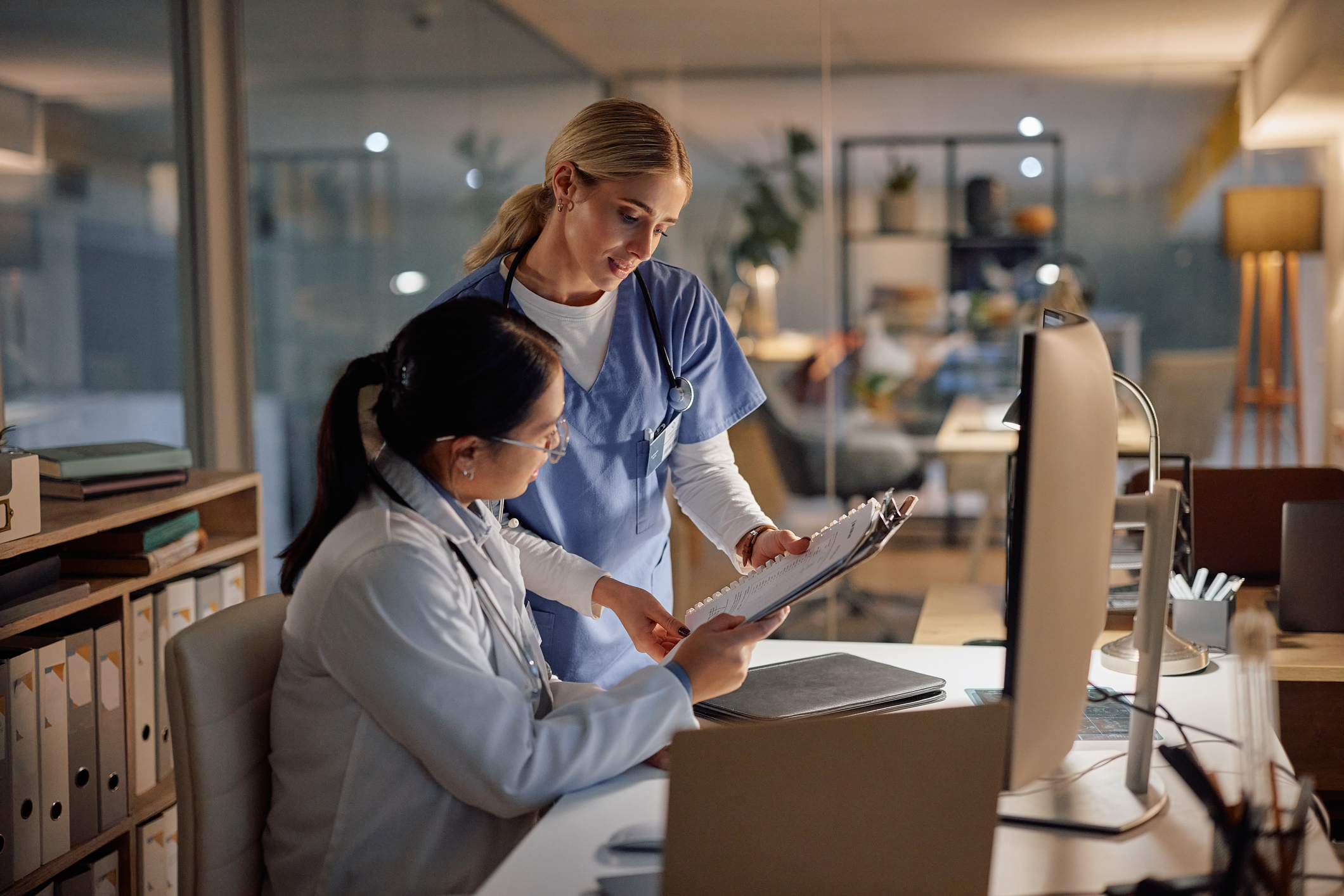 Doctor, nurse and colleague of computer paperwork for late night research deadline for diagnosis, problem solving or teamwork. Medical facility, office and document discussion, internet or decision