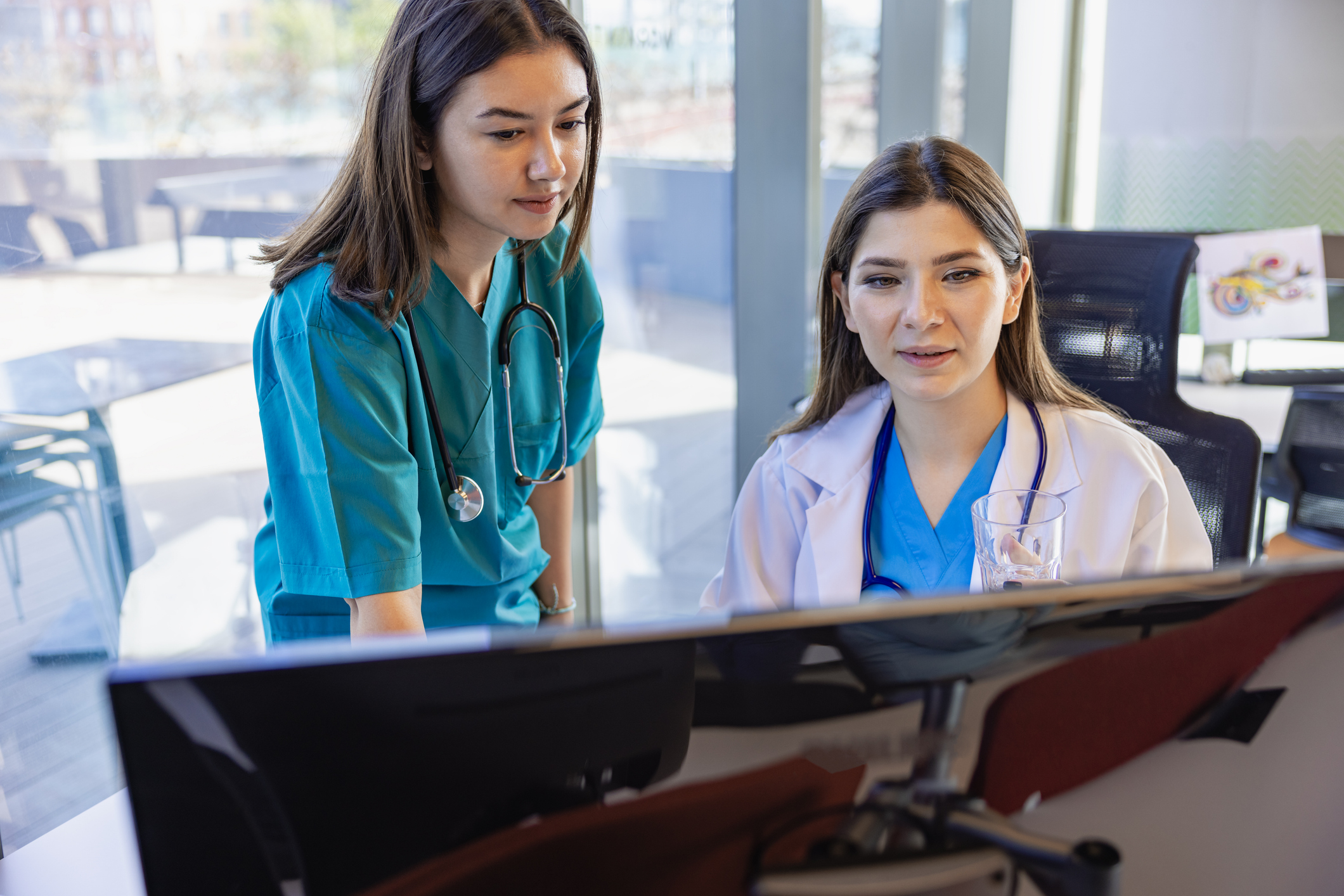 Two healthcare professional women are working on the computer