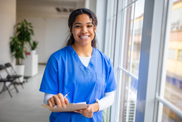 Smiling female nurse in scrubs takes notes