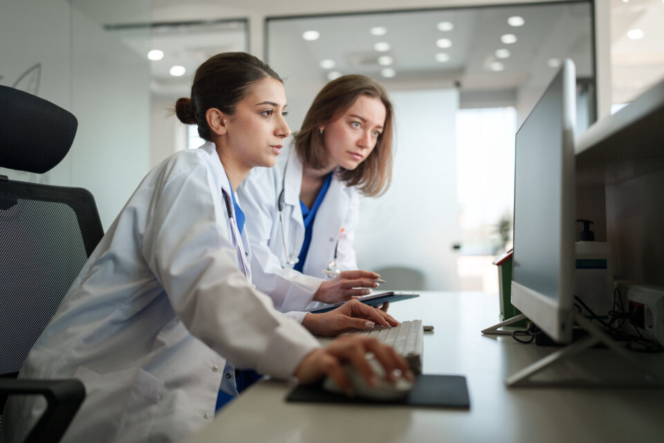 Two Female Healthcare Workers Focused on Computer and Cloud Faxing at Front Desk