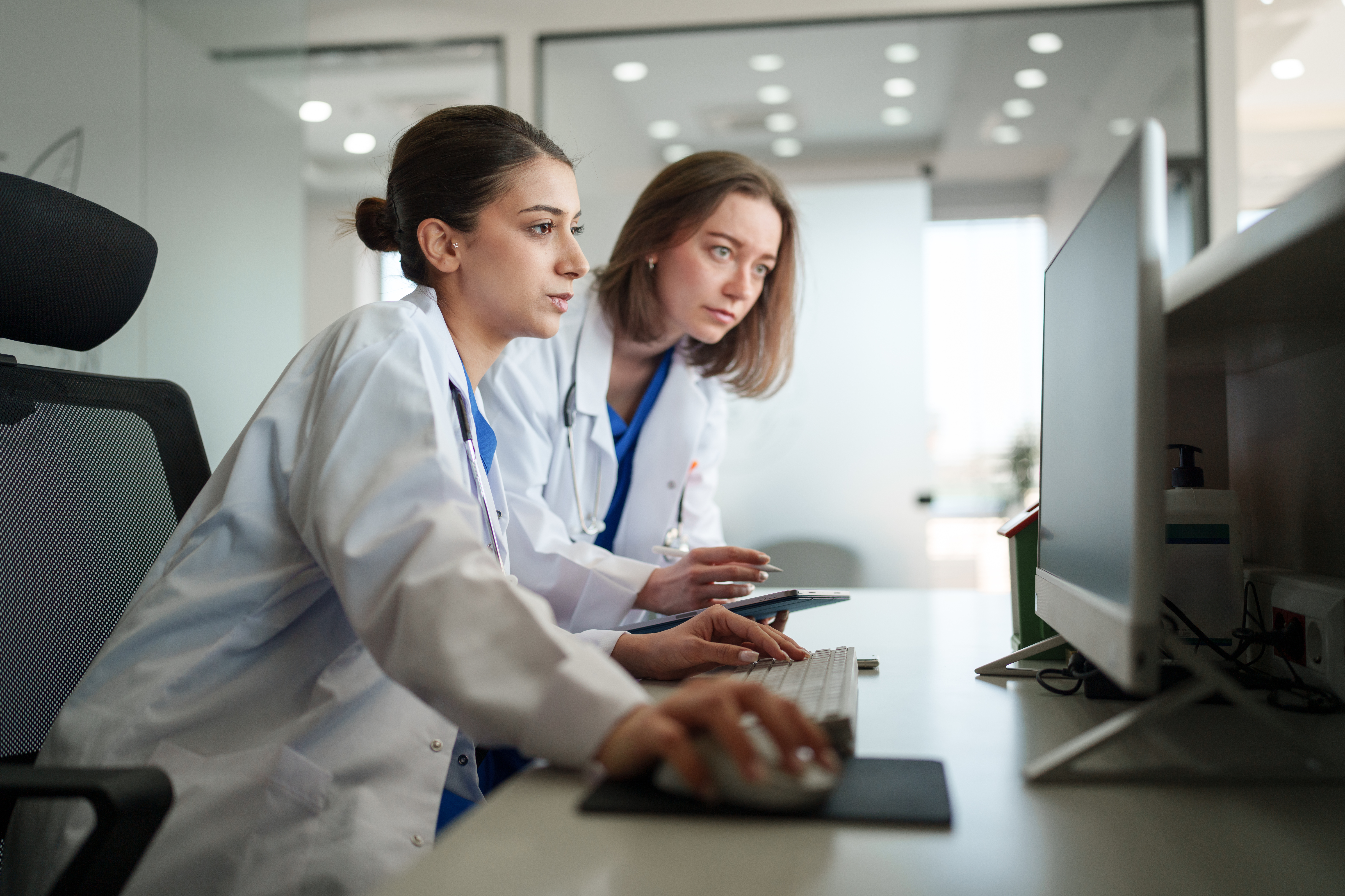 Two Female Healthcare Workers Focused on Computer and Cloud Faxing at Front Desk