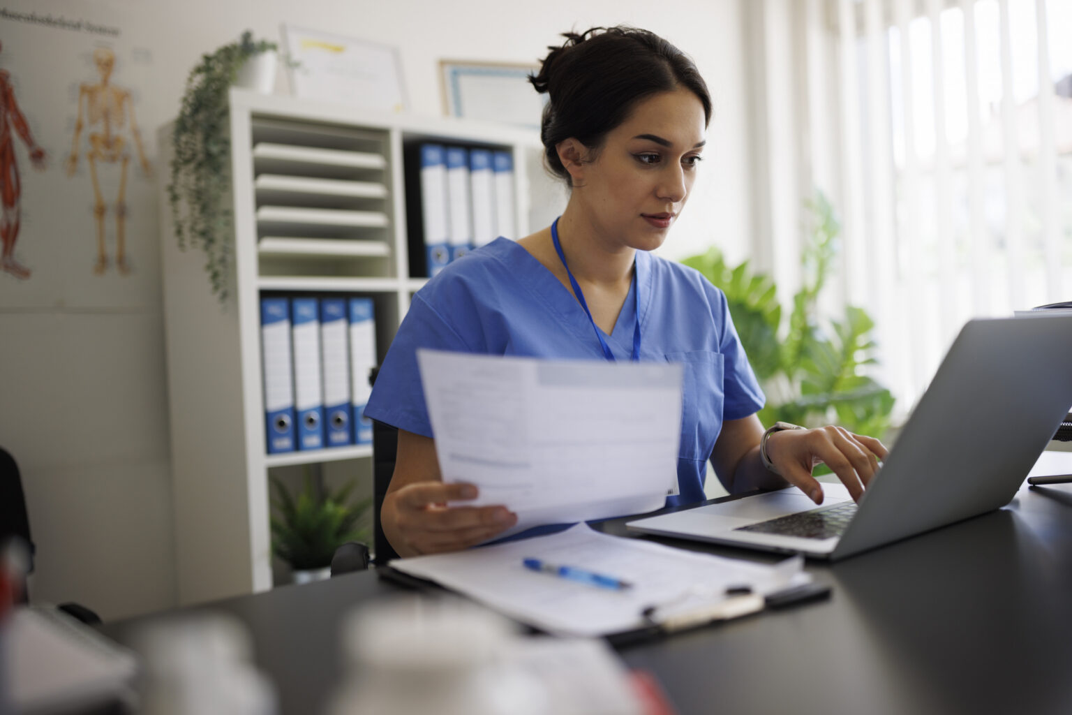 Focused young nurse processing fax documents with Documo's Cloud Fax