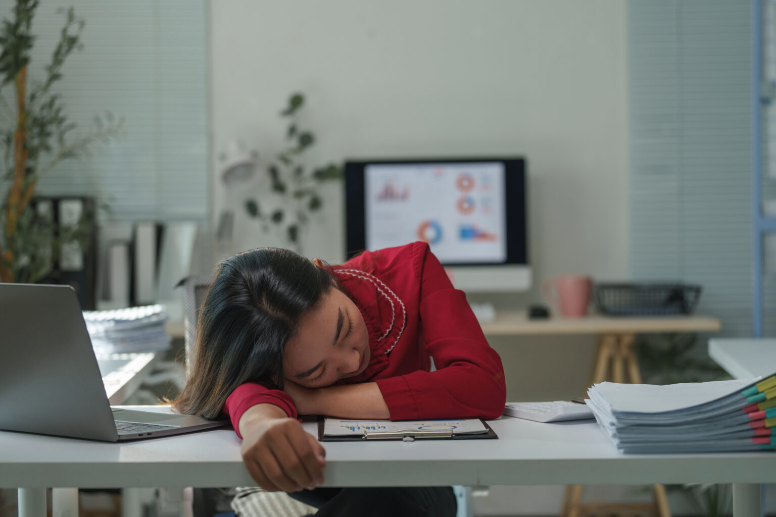 Young healthcare professional sleeping on desk at workplace, burnt out after a long day of computer work