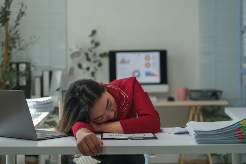 Young healthcare professional sleeping on desk at workplace, burnt out after a long day of computer work