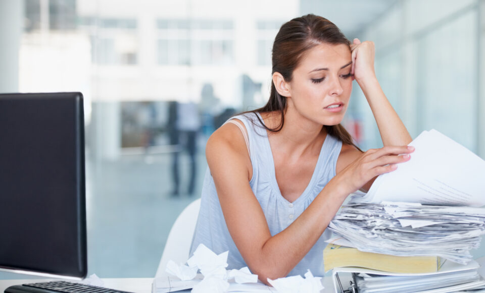 Stressed healthcare worker reviewing piled up paperwork