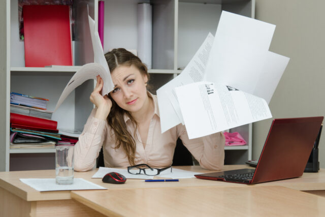 Young girl working at the desk in the office looking stressed