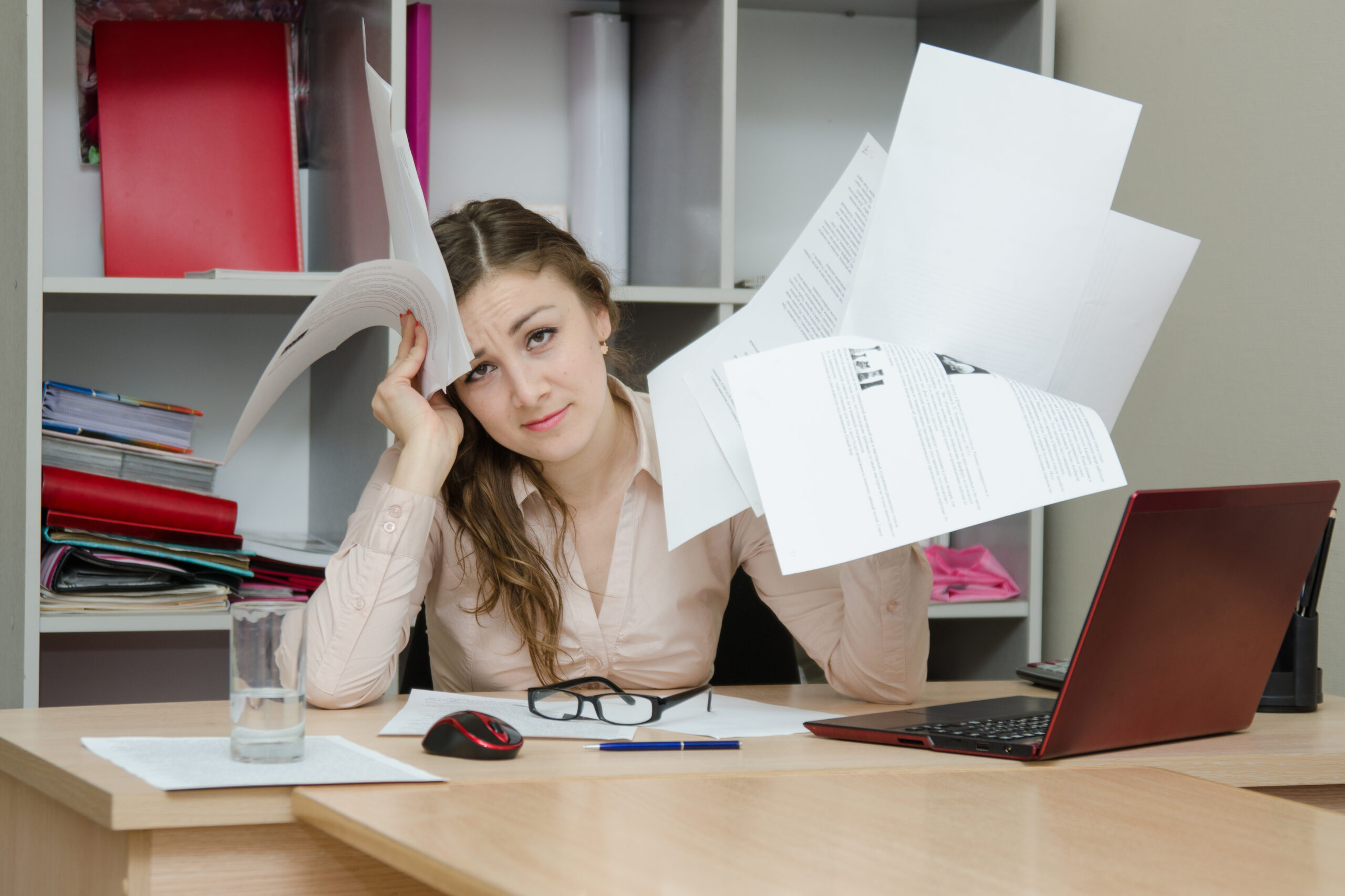 Young girl working at the desk in the office looking stressed